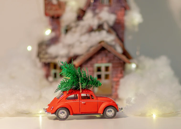 red car with christmas tree on top and a house in background