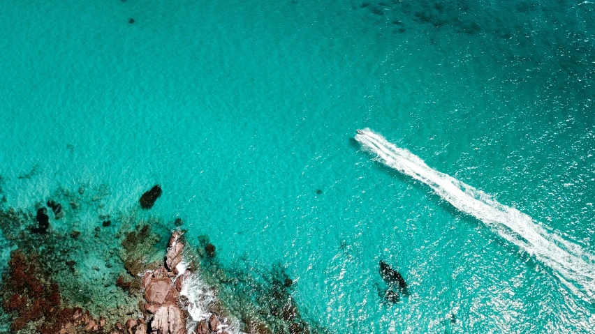 aerial view of an ocean, boat, and rocky beach