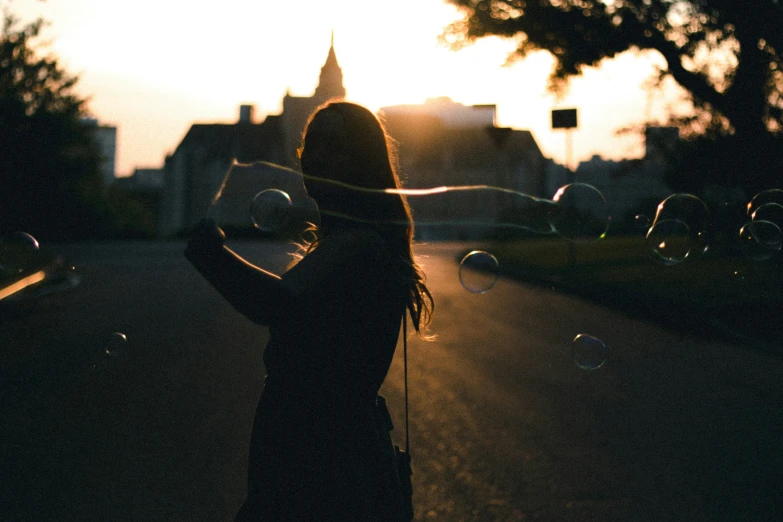 a girl blowing soap bubbles in the street