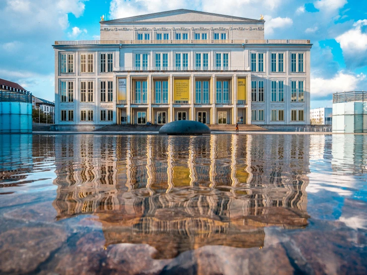 a large, historic building reflects in the calm water of a pond