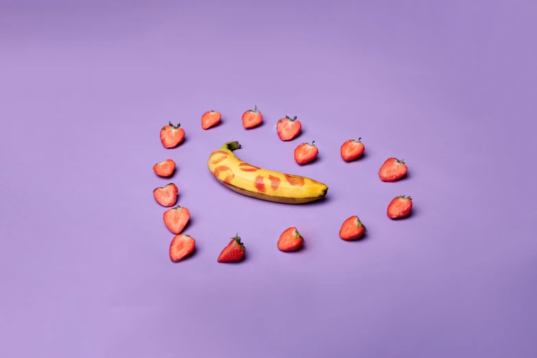 the banana is on its side as it lays among strawberries