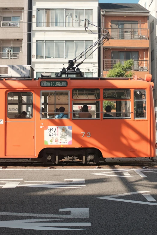 an orange bus with some people inside drives down the road