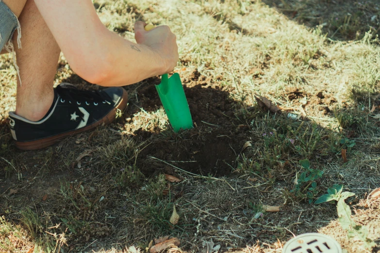 a person wearing black shoes and green cup in grass