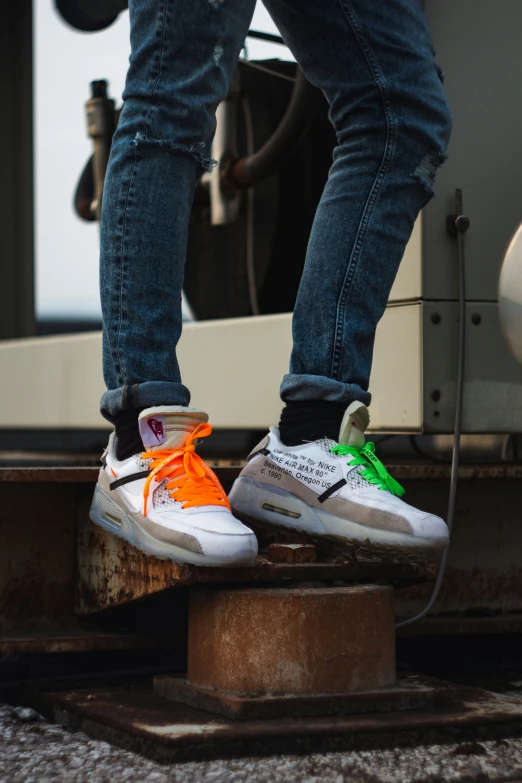 feet with neon sneakers and jeans stand on tracks