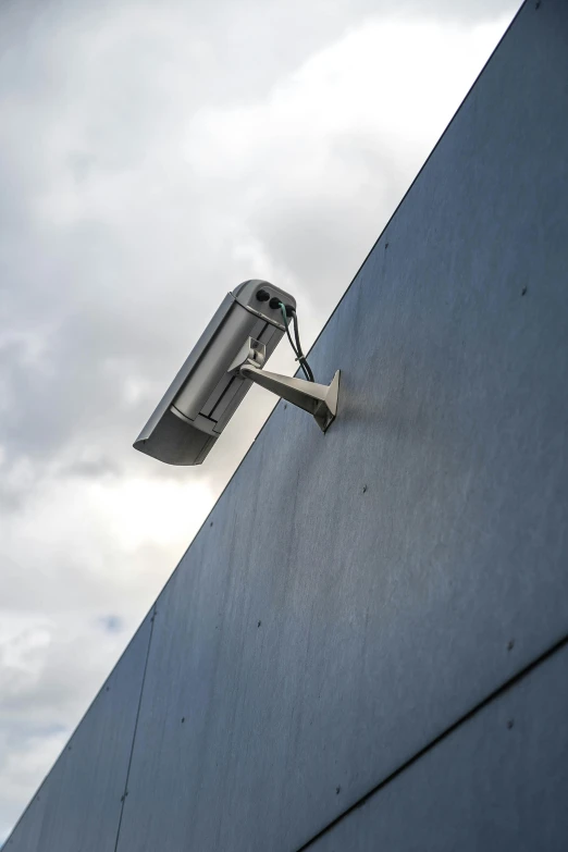 a metal security camera is mounted to a gray wall