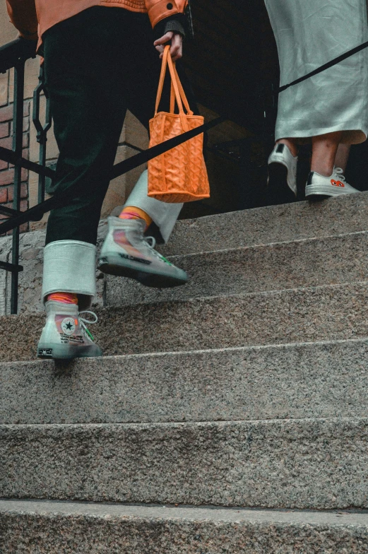 people stand on a stairs holding orange shopping bags