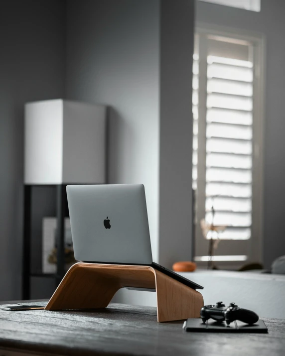 an apple macbook is sitting on a wooden stand