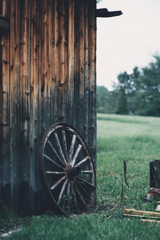 an old, wooden structure with a very old wheel on it