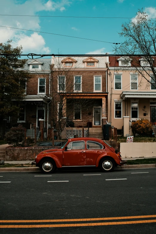 old red car parked in front of brick row houses