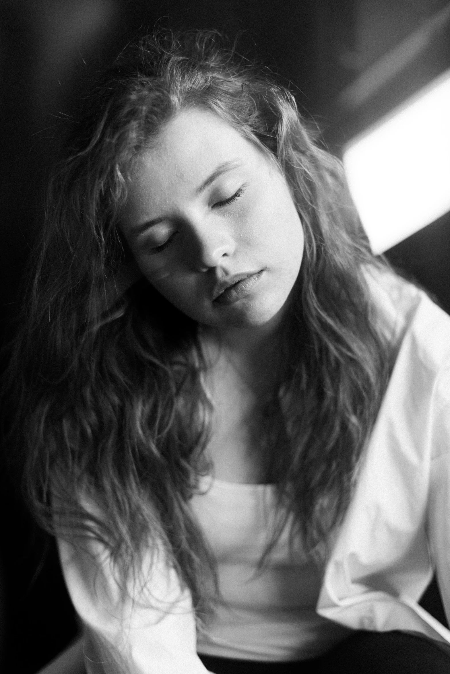 a young woman in white shirt sitting next to window