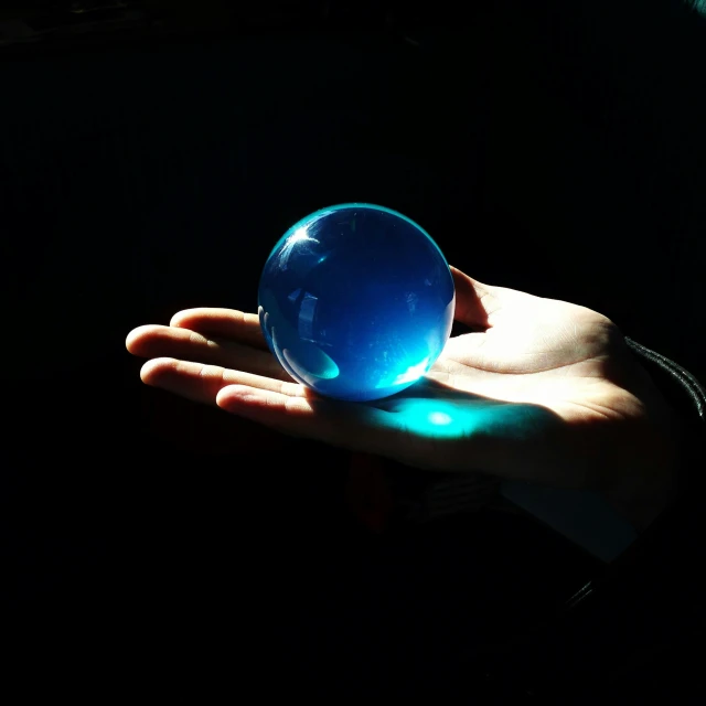 a man holding a large blue glass ball in his hand