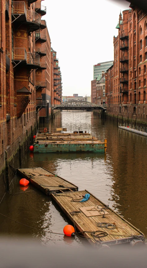 three boats floating in a canal between tall buildings