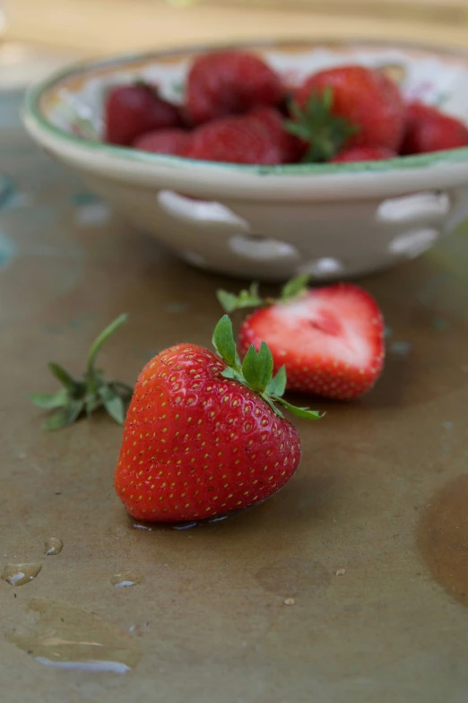 four fresh strawberries in a bowl on a table