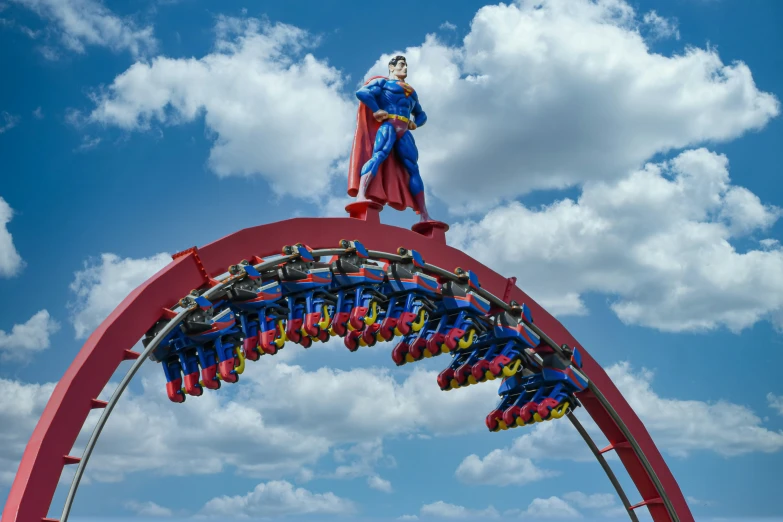 a statue of a man wearing a red cape and a cape sits on top of a roller coaster