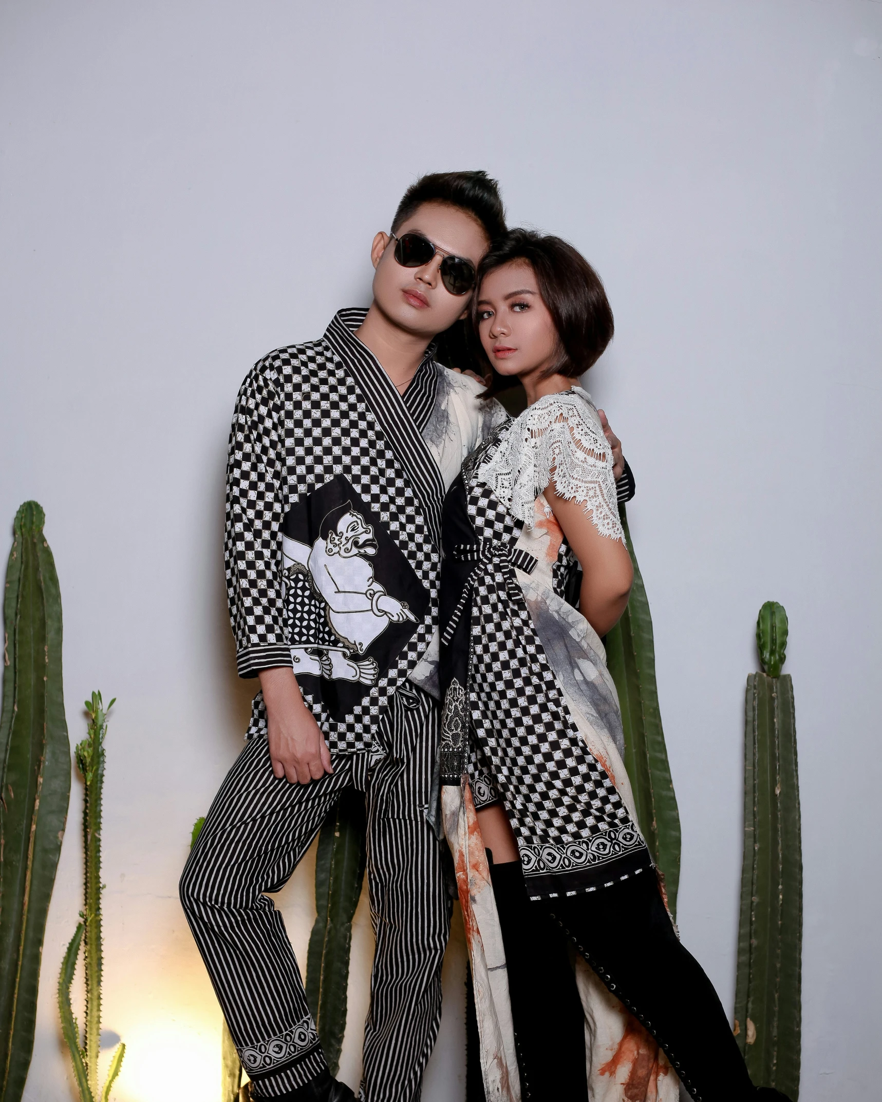 a young man and woman pose for a picture in front of cactus