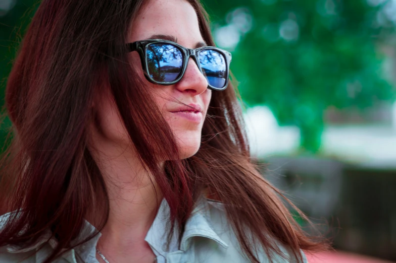 a young woman wearing sun glasses has long hair and is looking to the side