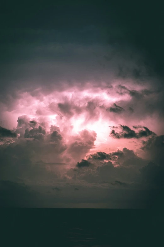 a group of clouds in a gray sky and blue sky with the light from underneath