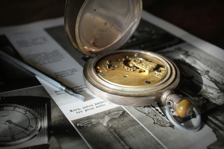 a pocket watch with a gold face is sitting on a piece of paper