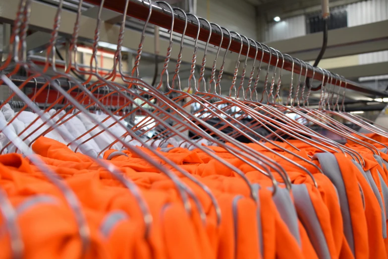 orange and white shirts hang in a factory