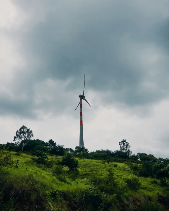 a wind farm atop a grassy hill in the background