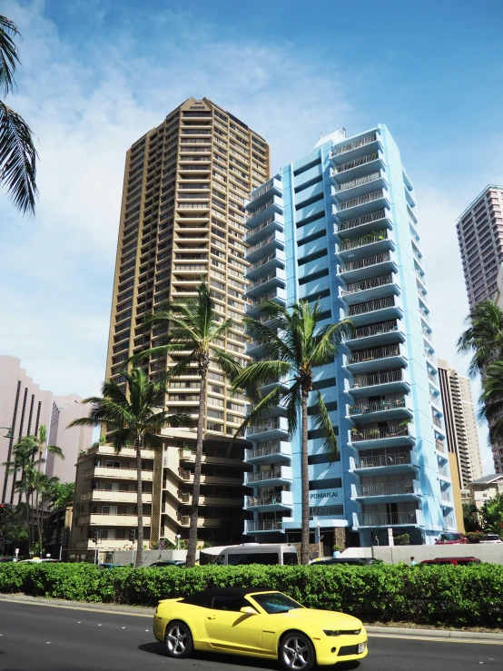 a yellow sports car is parked by two tall buildings