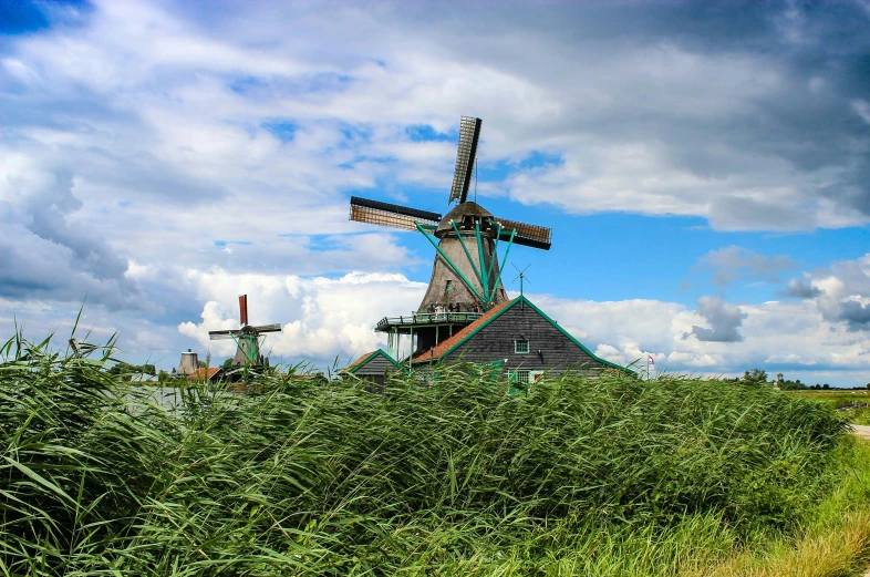 three windmills stand beside a green grassy field