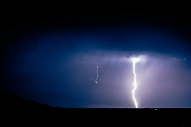 a lightning strikes the sky above a field