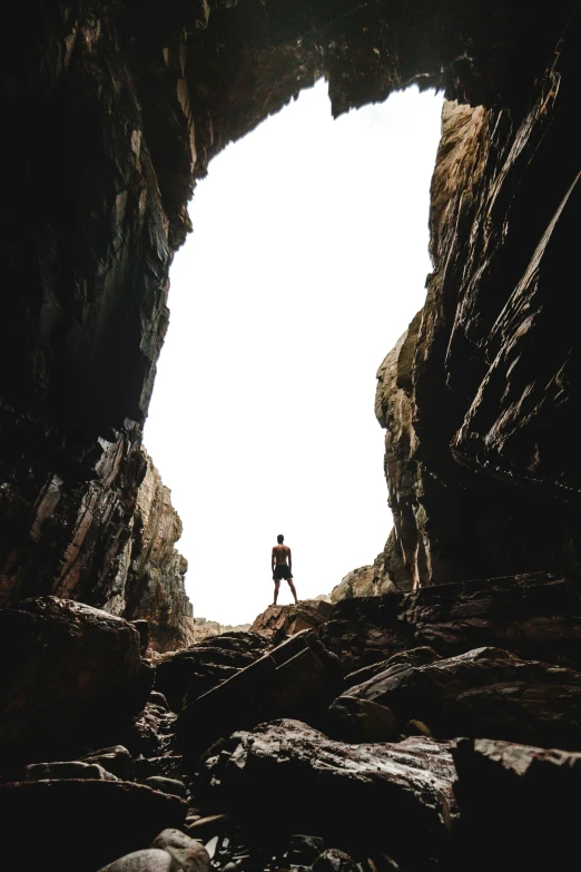 a man is standing on the rock near a cave