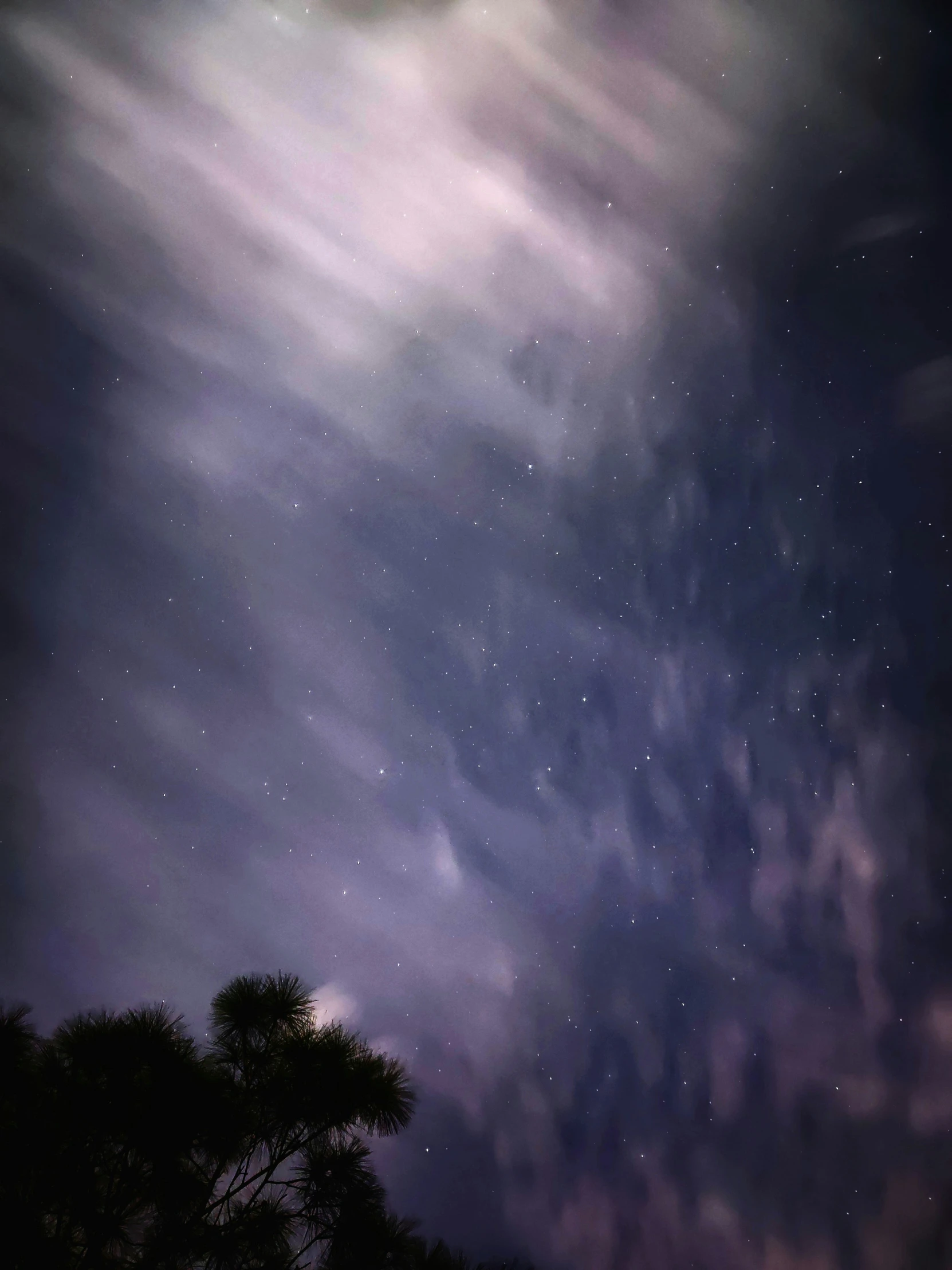 the night sky with some clouds and stars above