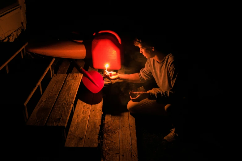 a person sitting down on a bench with a candle in their hand