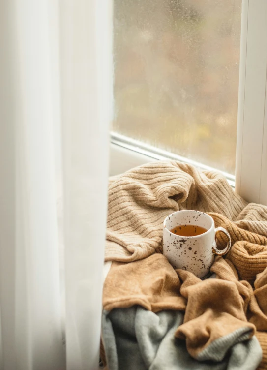 a cup of coffee and a blanket on the floor