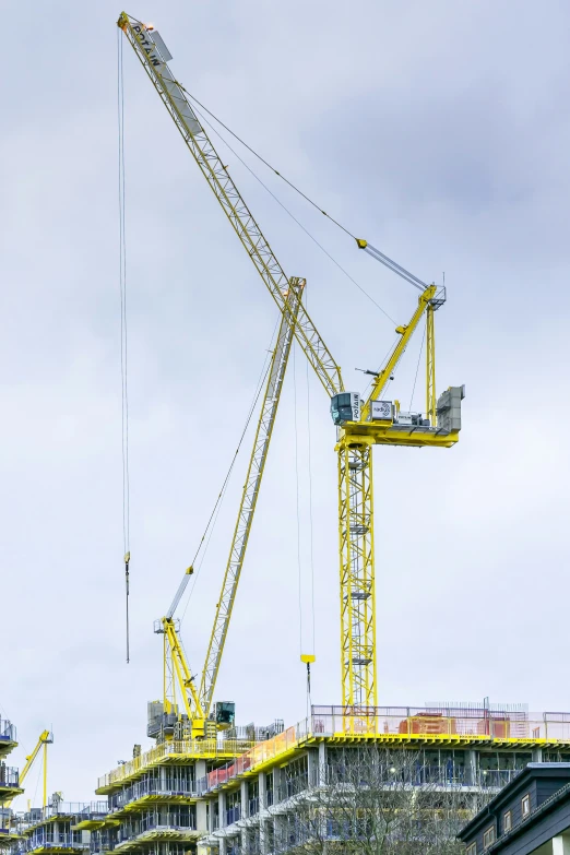 two yellow cranes on top of a building under construction