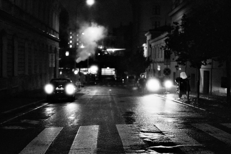 an empty street with cars passing by in the night