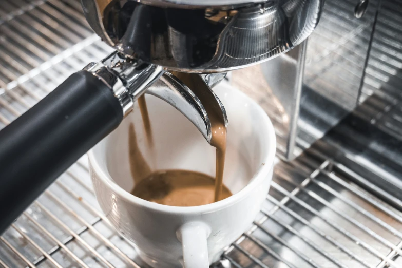 espresso being poured into a cup with a black handle