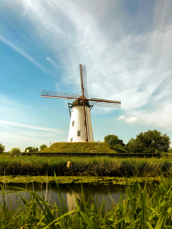 a windmill stands in a field next to a lake