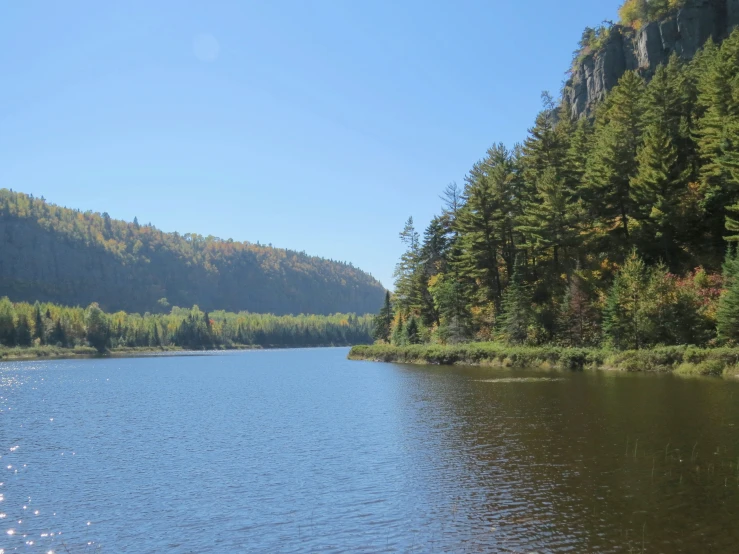 a lake surrounded by trees, mountains and blue sky