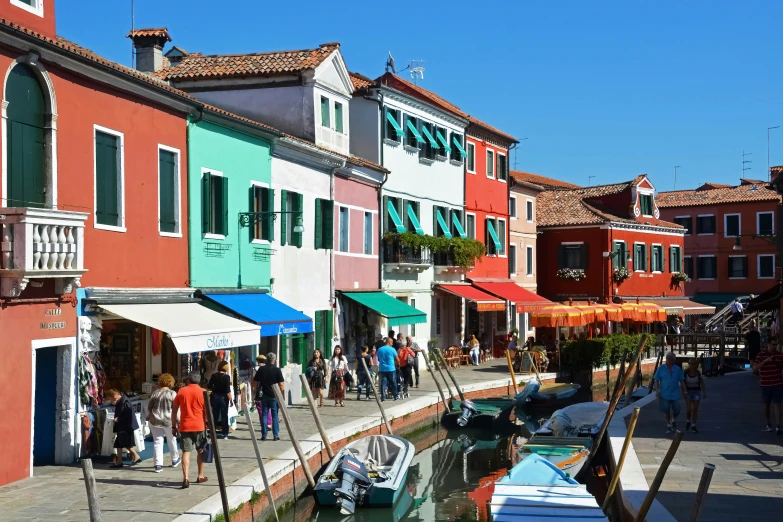 a group of people standing outside of houses on a canal