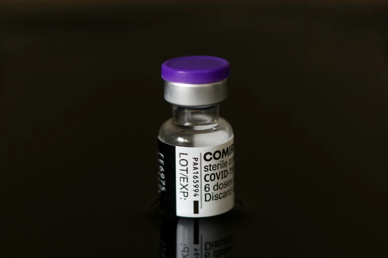 a small purple pill bottle with a black top