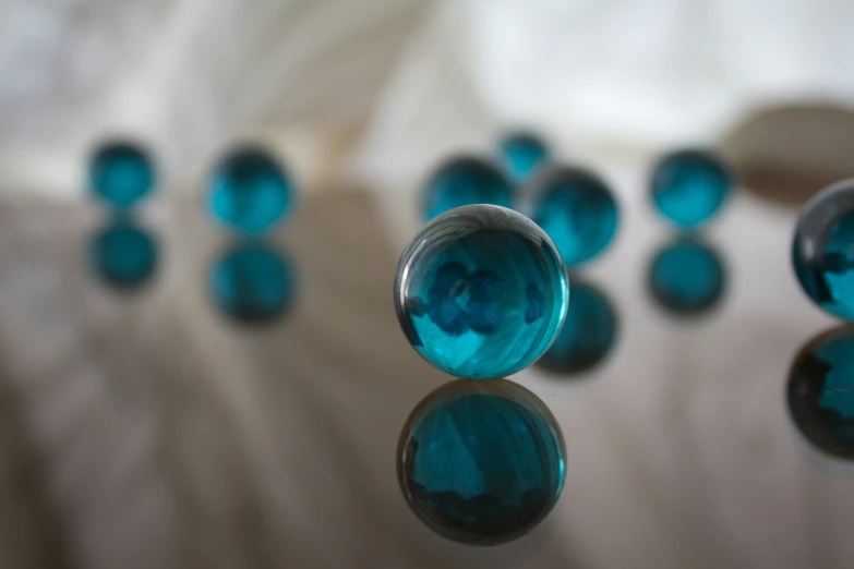 several small blue glass spheres are reflected in the water