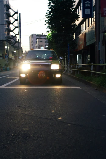 the front end of a car driving down a road at dusk