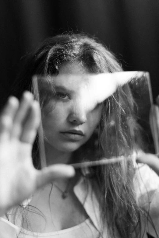 a woman holds out her hands behind a mirror