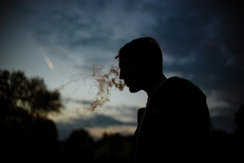a man smoking a cigarette in the evening