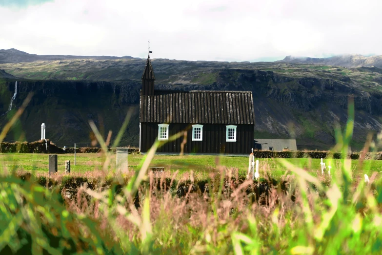 a black church sits on a lush green mountain