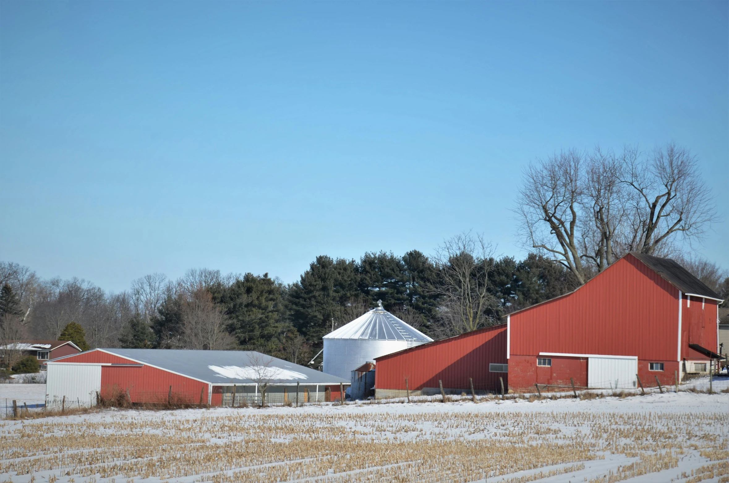 a red barn with two large white silos