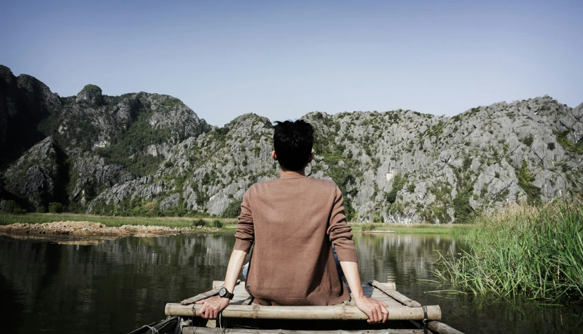 a man sits in a small boat on the water