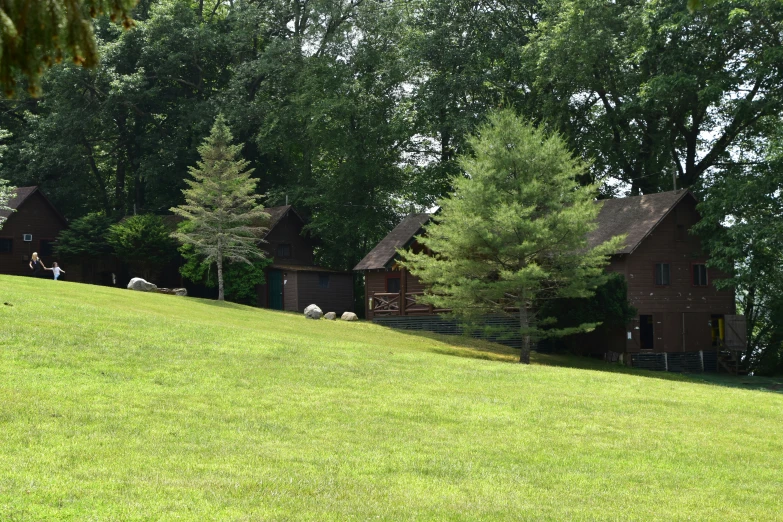 a row of brown cabins sitting on top of a lush green hillside