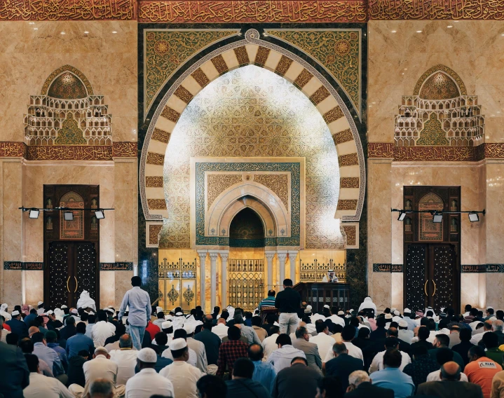 a person with a veil on his head and several people around him are sitting down at prayer