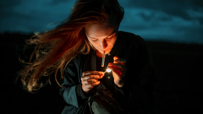 a woman holding a lighter standing in front of a black background