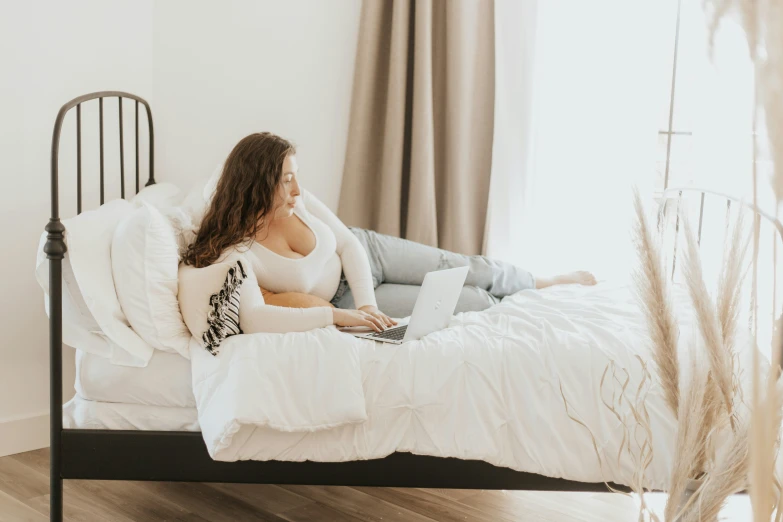 a woman laying on her bed working on a laptop