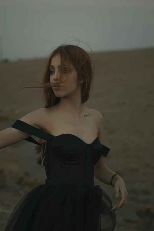 a woman in a black dress posing in a field